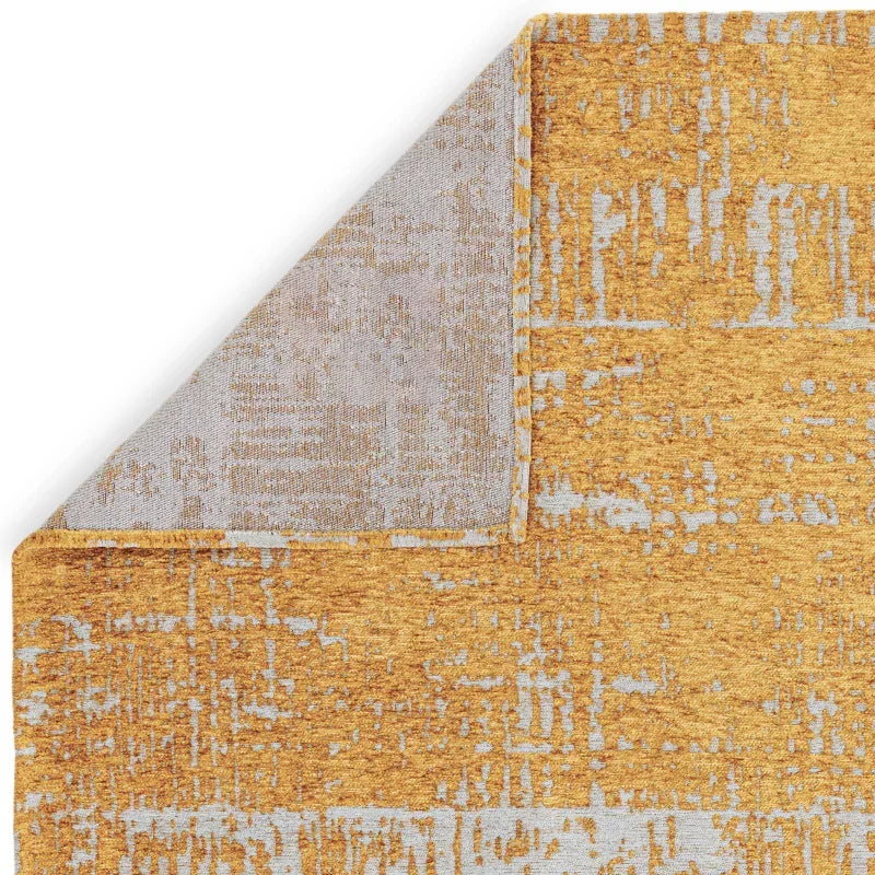 Yellow and grey abstract pattern area rug with folded corner showing backing