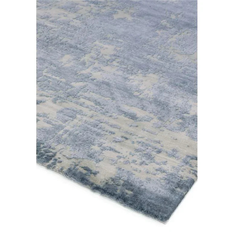 Blue and cream abstract pattern area rug with soft textured pile, close corner view