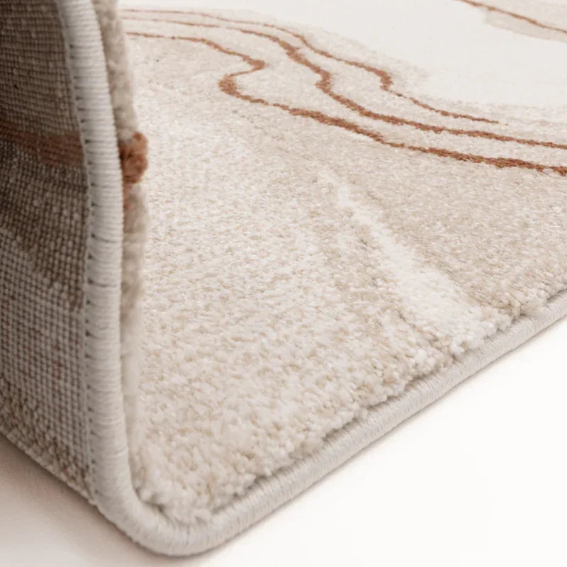 Beige patterned rug close-up showing soft textured pile and edge stitching detail
