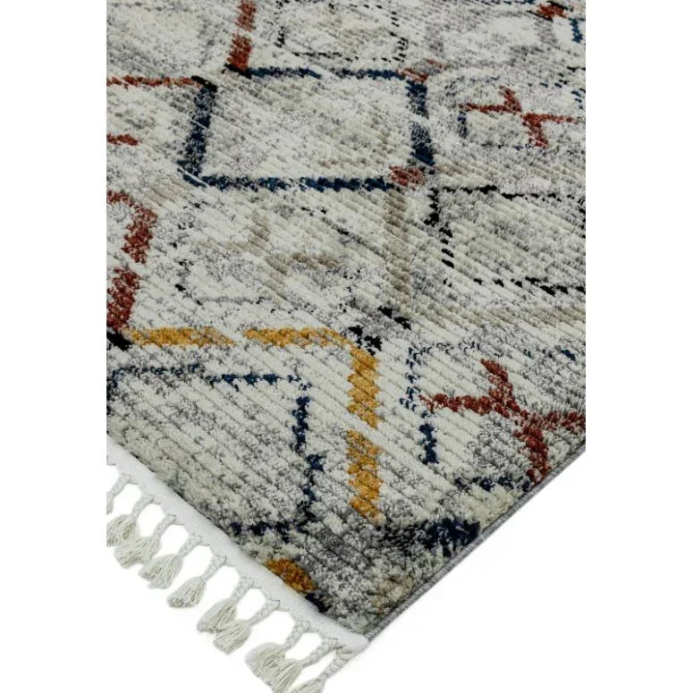 modern rug with geometric pattern in grey, yellow, blue, and red, showing tasseled edge