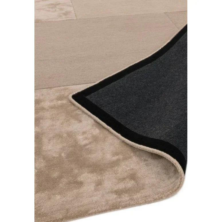 Beige area rug with soft textured surface and black non-slip backing, corner folded up