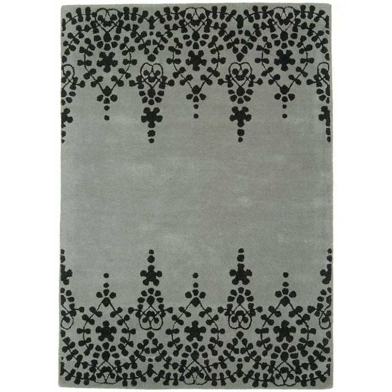 Grey area rug with black ornate border pattern and soft textured surface