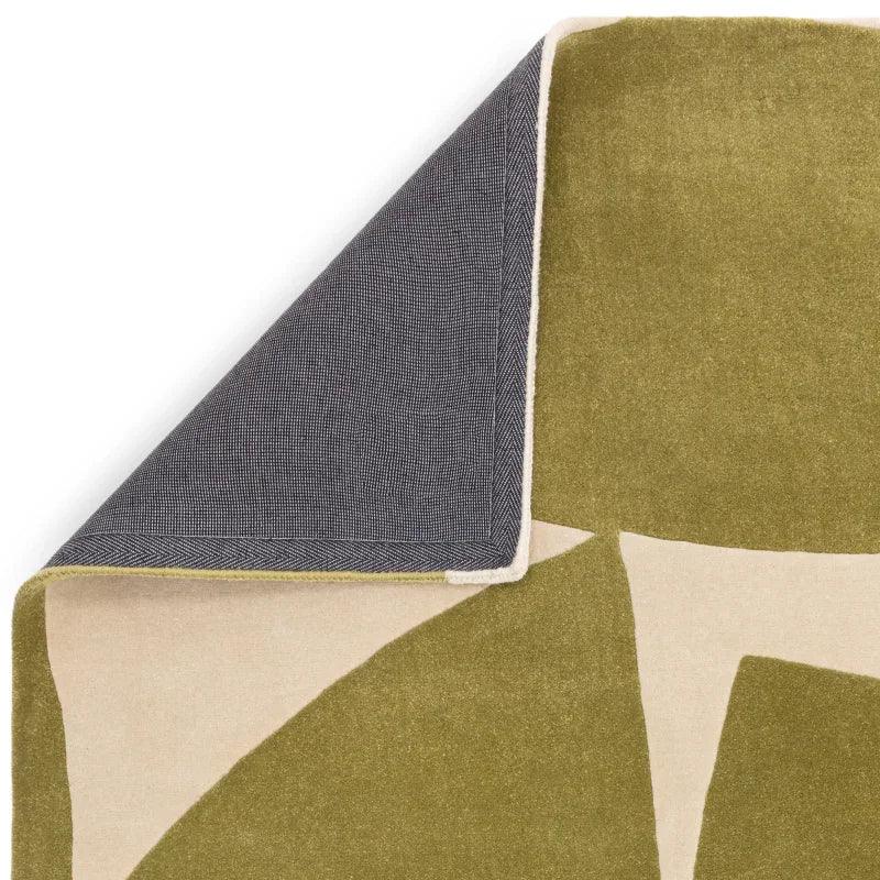 Closeup of green and cream abstract rug with corner flipped to show grey backing