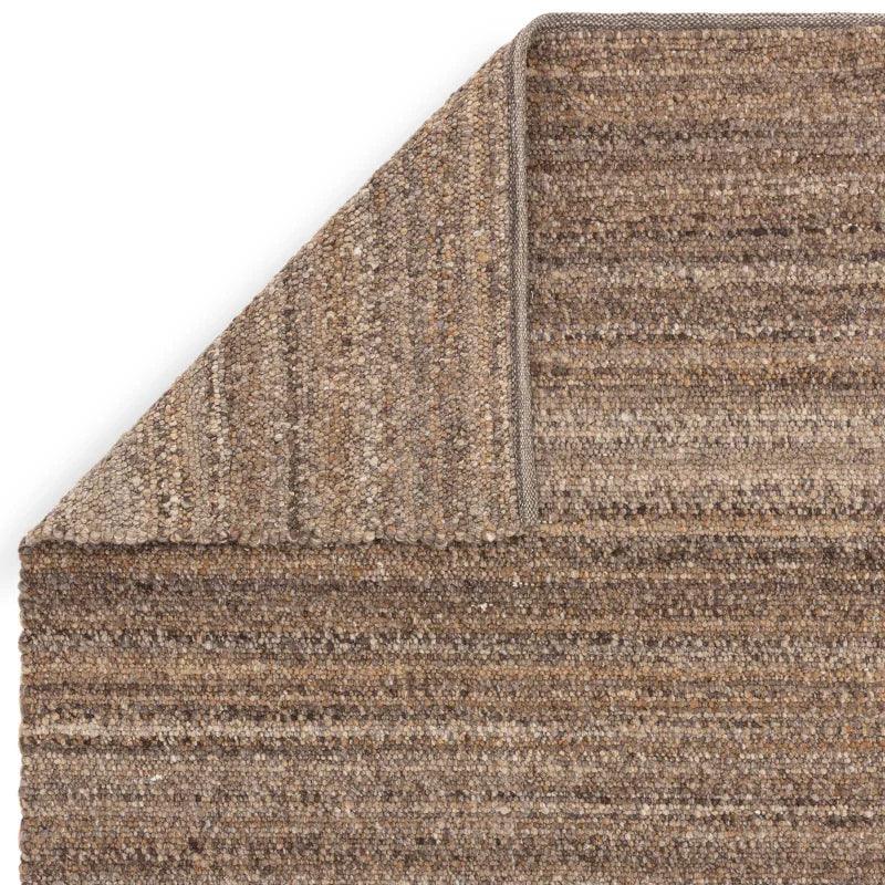 Brown textured wool rug with corner folded to show backing detail