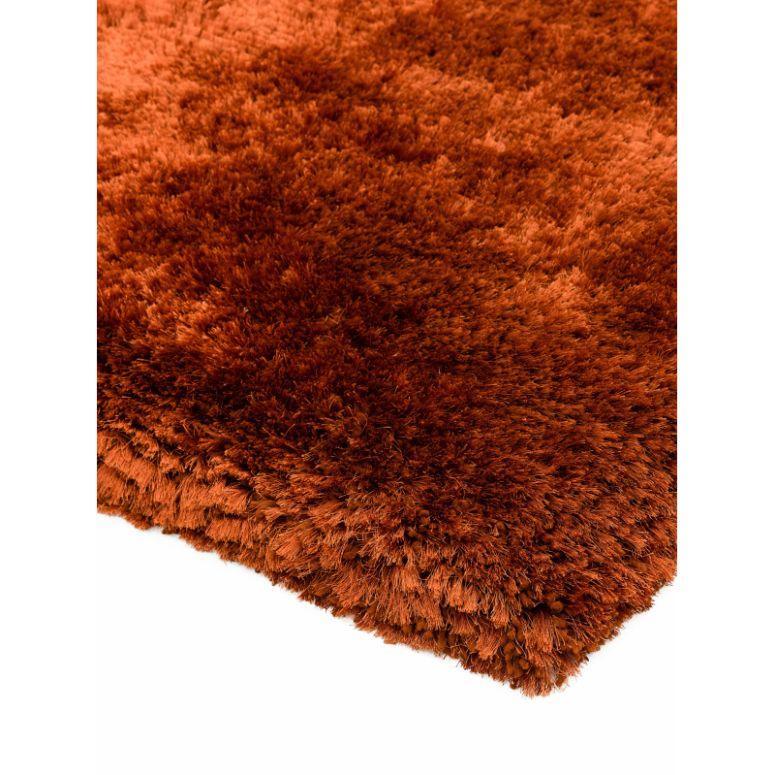 Close-up of rust orange shaggy rug with thick, soft pile and textured surface