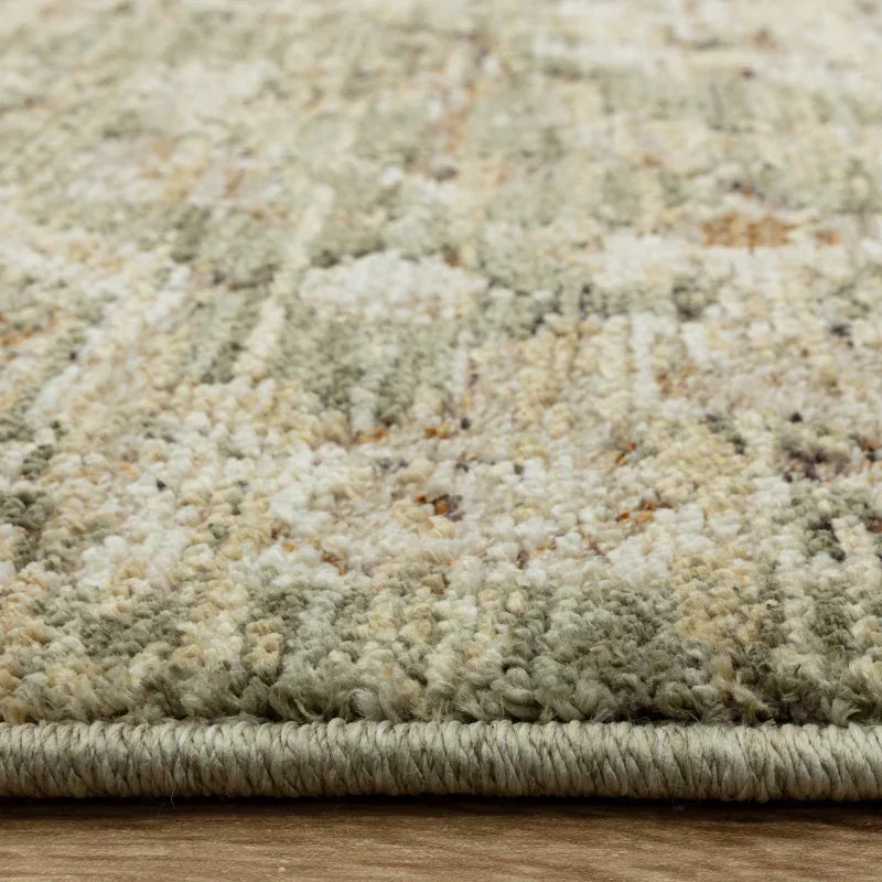 Closeup of beige and green area rug edge on wooden floor showing texture and pile