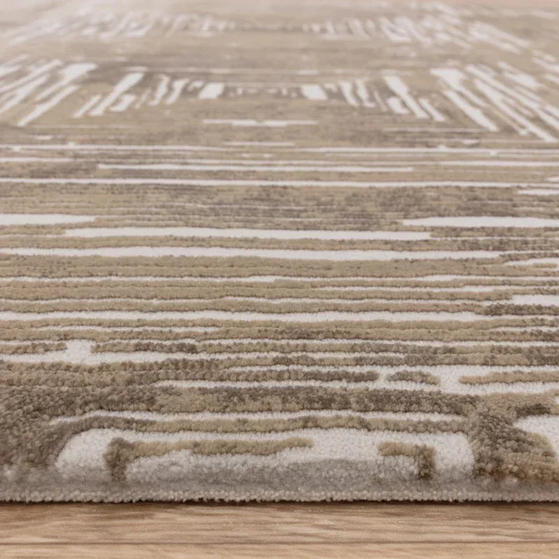 Beige and cream area rug with textured abstract pattern on wooden floor, side angle view