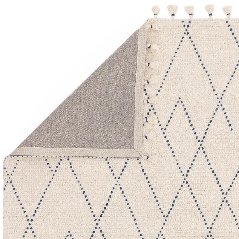 Ivory textured rug with navy diamond pattern and tassel edge, corner detail shown