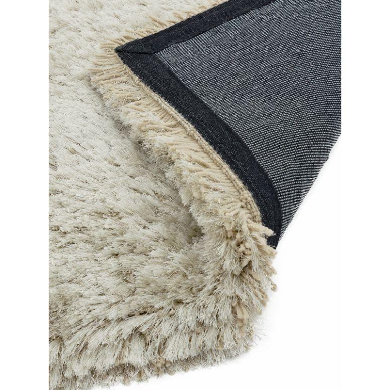 Close up of beige shaggy rug with soft pile and dark woven backing