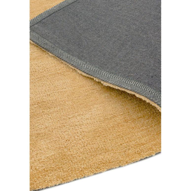 Close-up of beige area rug with soft pile and woven fabric backing