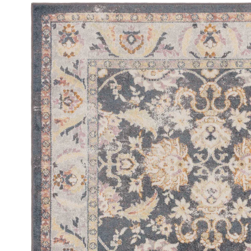Blue and cream patterned area rug with floral and scroll border detail, corner close-up