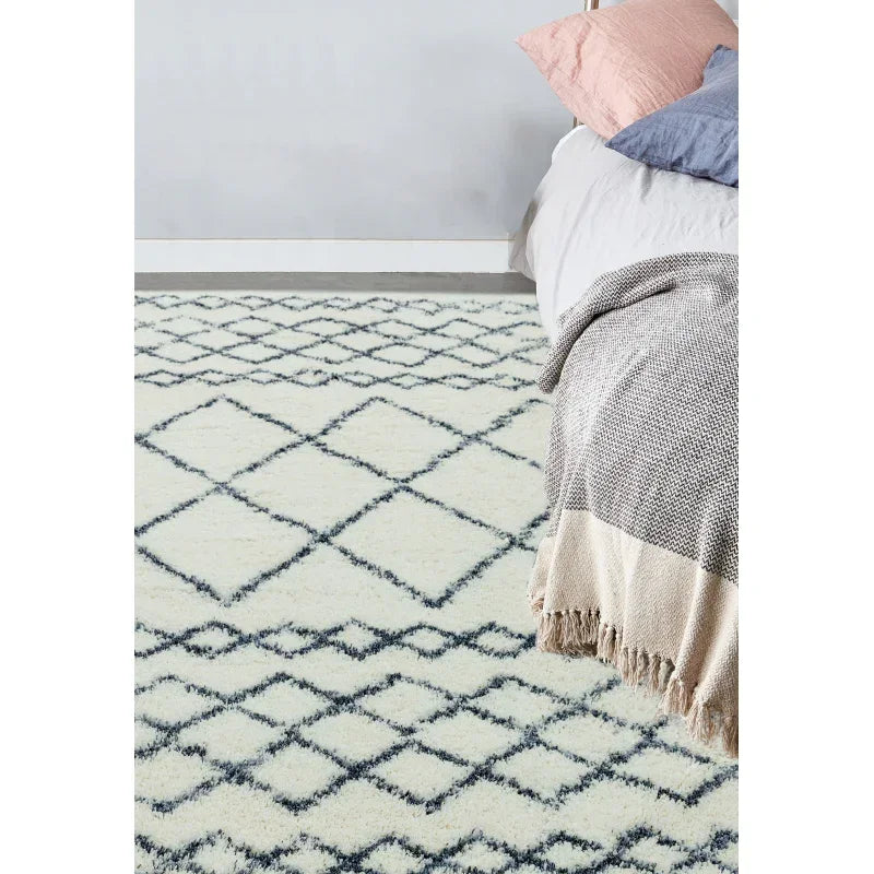 Cream geometric patterned rug in bedroom with double bed and layered blankets