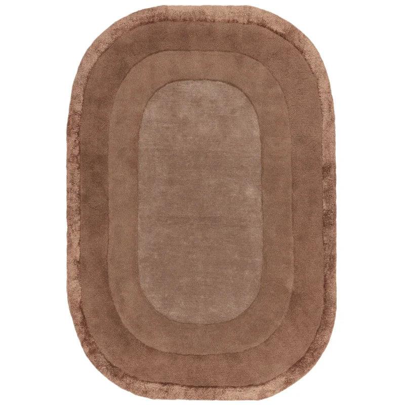 Oval brown area rug with plush texture and layered border design