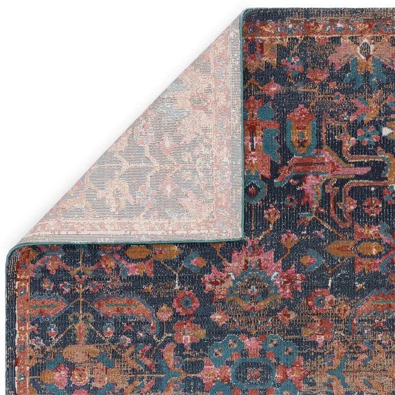 Navy floral patterned rug with one corner flipped to show underside detail