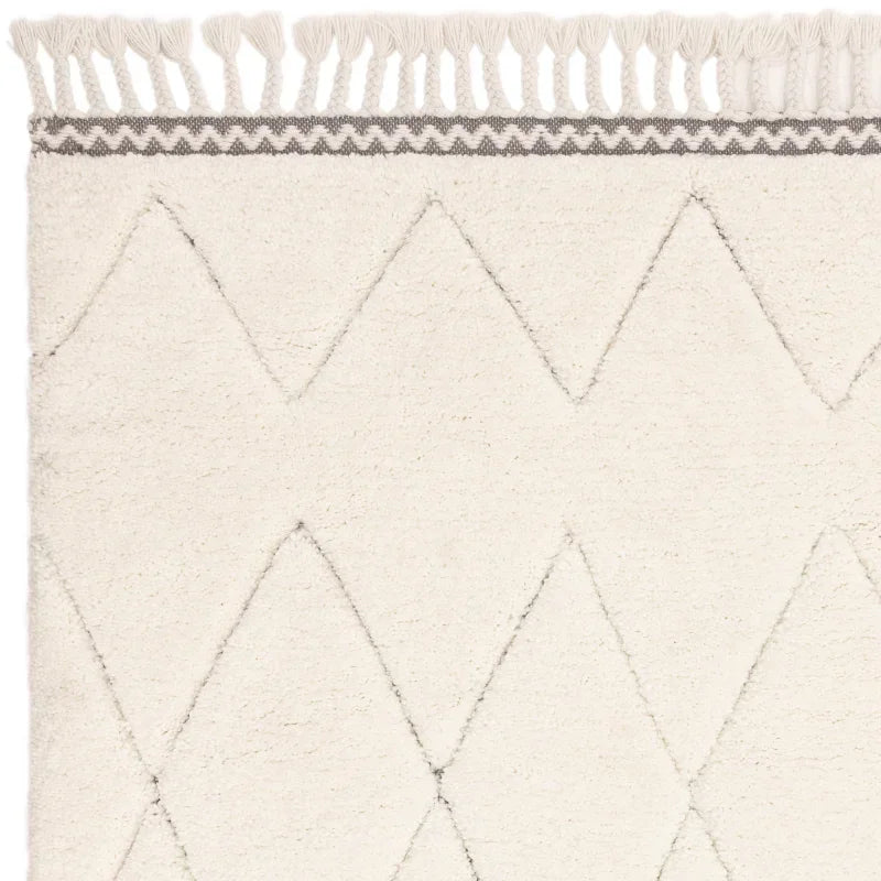 Cream patterned rug with grey geometric lines and tasselled edge closeup