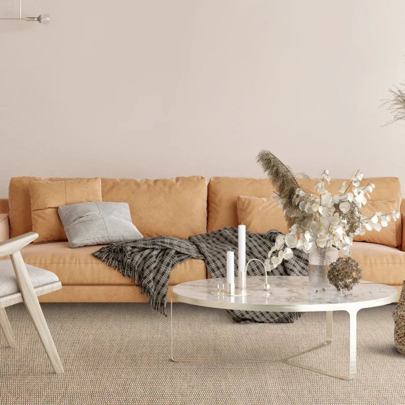 Tan fabric sofa with grey cushion and throw, marble coffee table with vase and candles