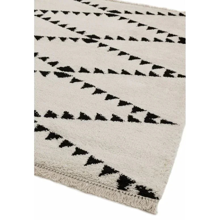 cream area rug with black geometric triangle pattern and textured fringe edge