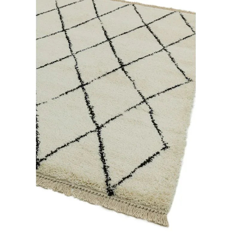 Cream shaggy rug with black diamond pattern and fringe detail on corner
