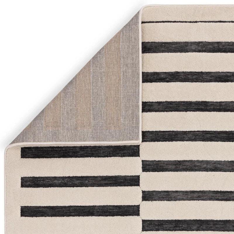 Modern striped area rug in black and cream with corner folded to show backing