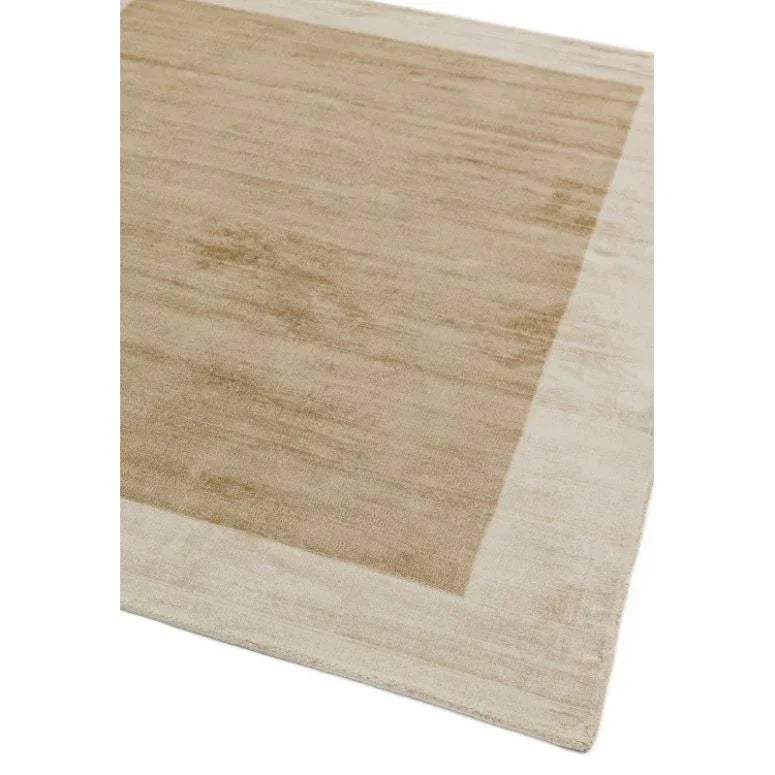 Beige area rug with solid center and lighter border, close corner view on white background