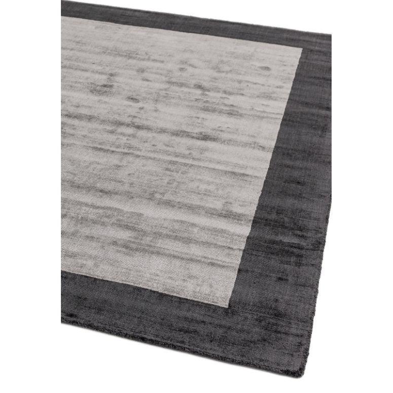 Rectangular area rug with light grey center and dark grey border, close corner view