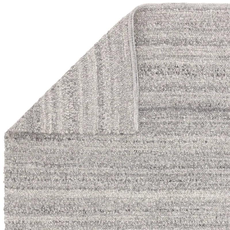 Light grey textured area rug with folded corner showing weave detail