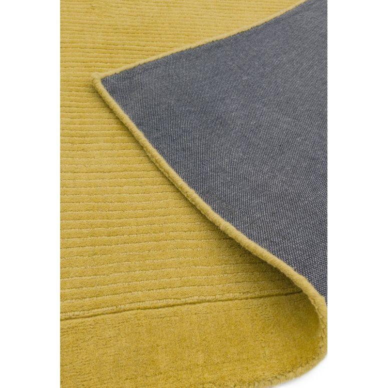Yellow striped area rug corner folded to reveal grey backing and textured surface