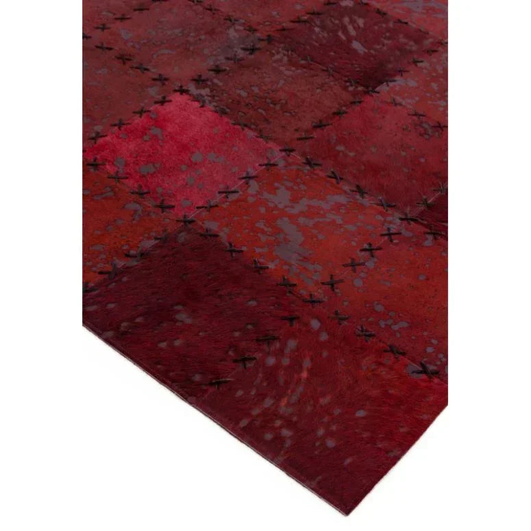 Red patchwork area rug with cross-stitch detailing and speckled pattern close-up