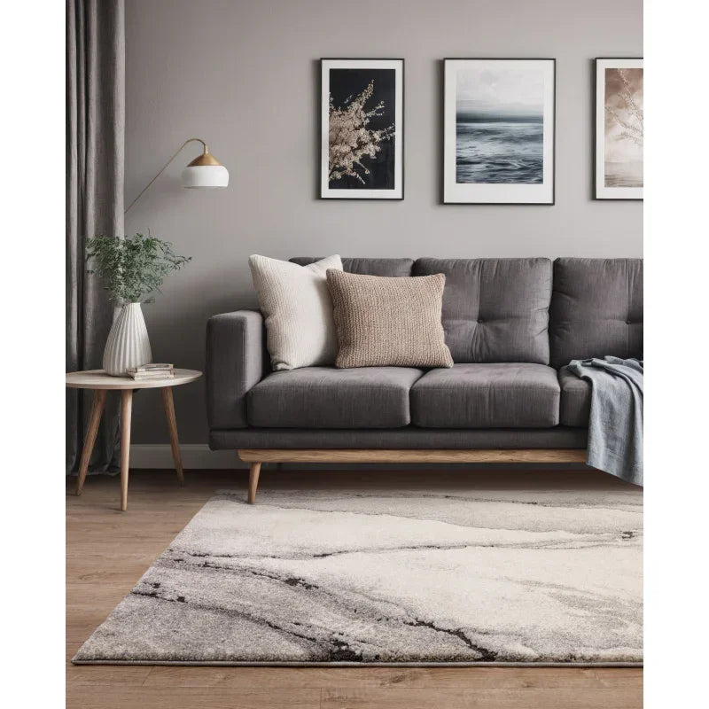 Grey fabric sofa with cushions, modern rug, wooden side table and wall art in living room