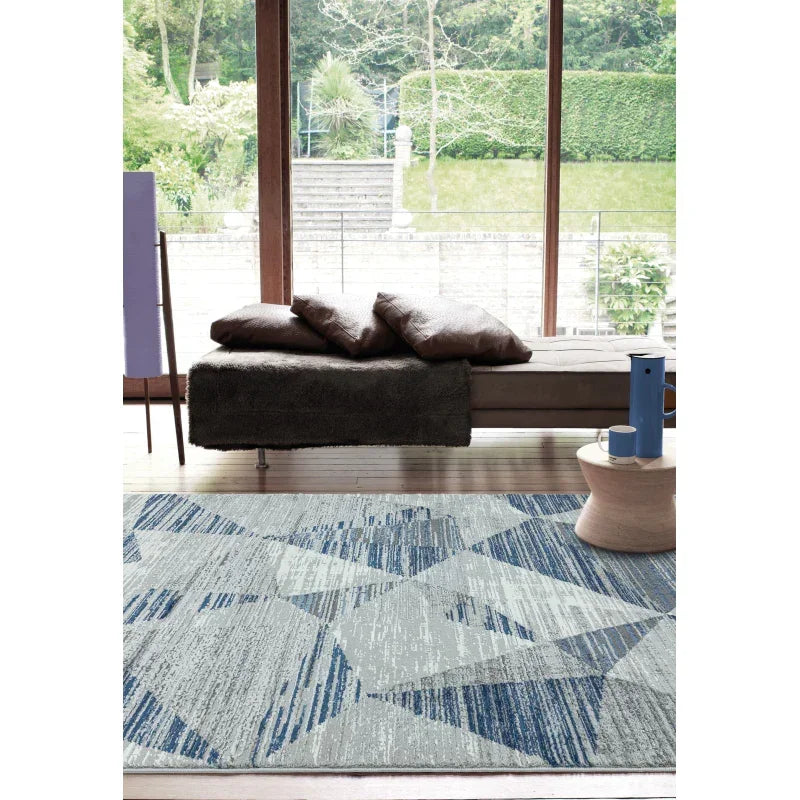 Modern geometric patterned rug with blue and grey tones in a bright living room