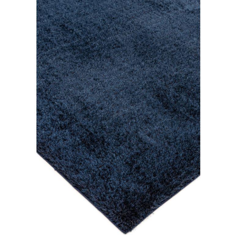 Navy blue shaggy rug with deep pile, close-up view of textured corner