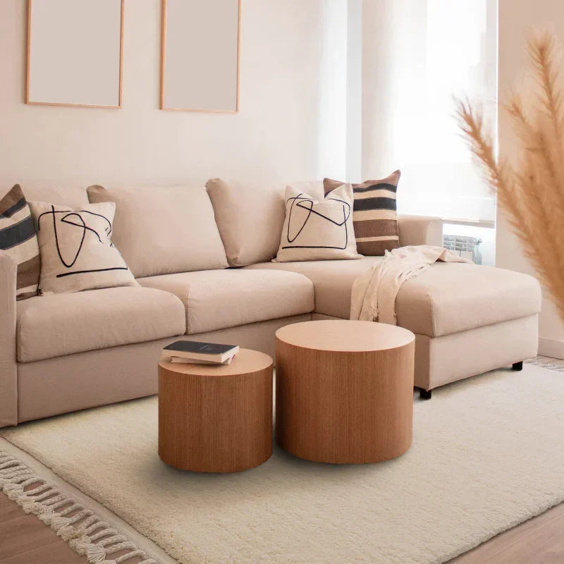Beige corner sofa with abstract cushions and round wooden coffee tables in modern living room