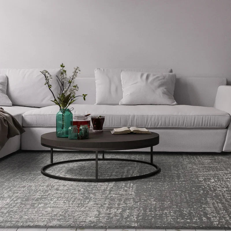 White fabric sofa with plush cushions and round coffee table on a grey patterned rug