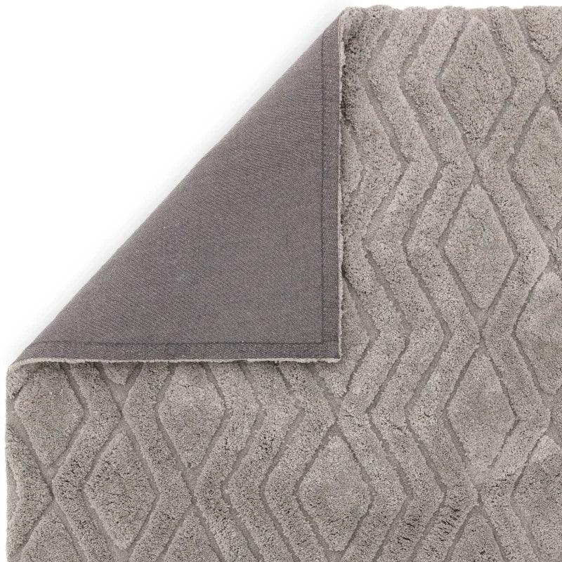 Grey geometric patterned rug corner folded to show texture and backing