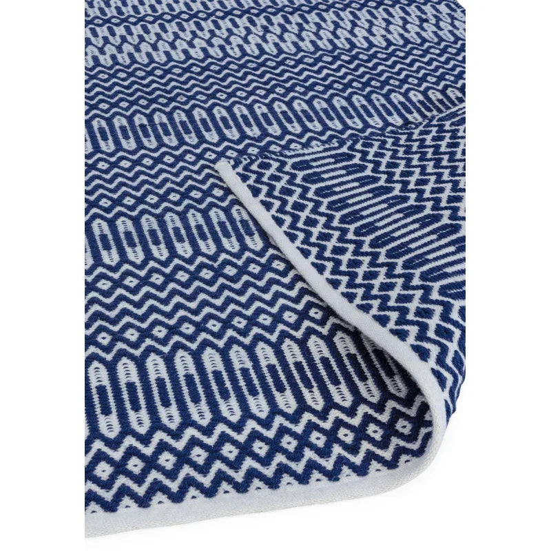 Blue and white geometric patterned rug with folded corner showing woven texture
