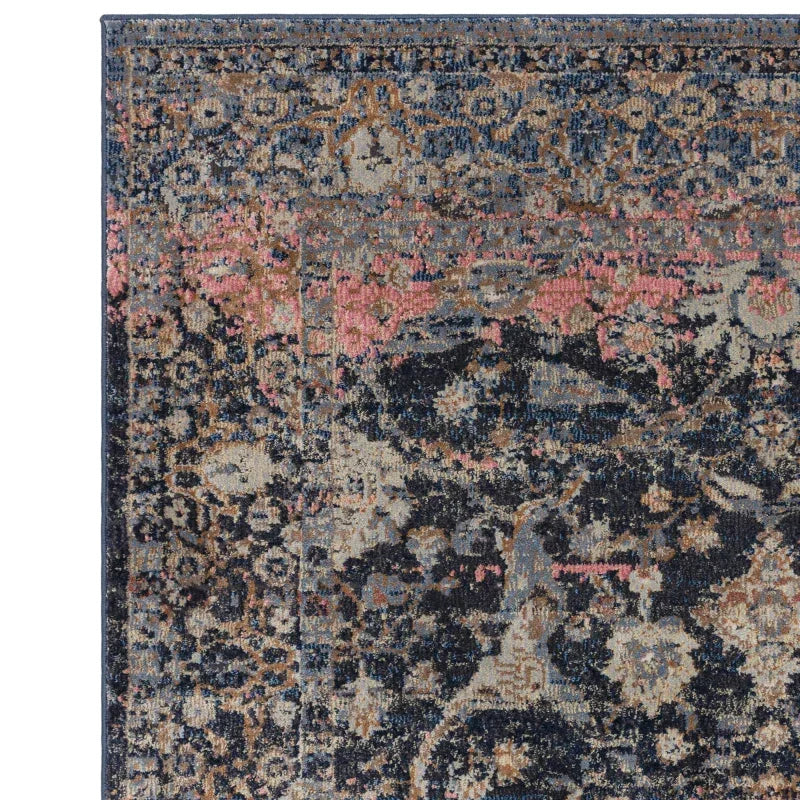 Corner detail of vintage style area rug with dark blue, beige, and pink floral pattern