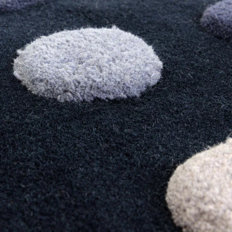 Close-up of textured wool rug with raised grey and cream polka dots on a dark background
