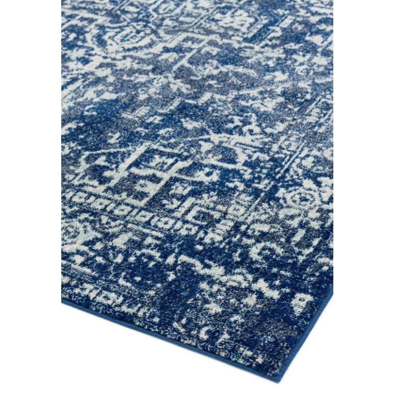 Blue patterned area rug with distressed white geometric design, close-up corner view