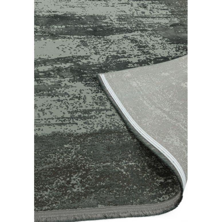 Modern grey area rug with textured pattern and corner folded to show backing