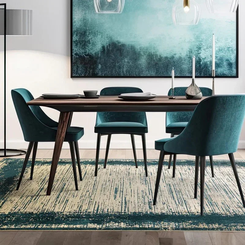 Modern dining table set with teal velvet chairs on patterned rug in contemporary room