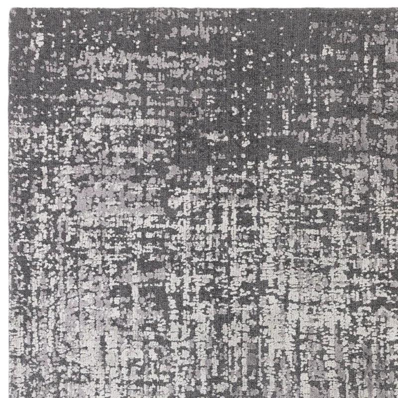 Grey abstract area rug with textured pattern and soft pile, close-up corner view