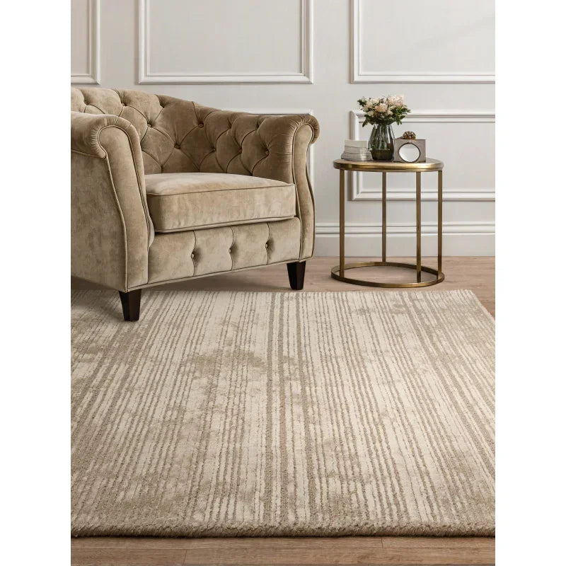Beige patterned area rug in living room with tufted armchair and round gold side table