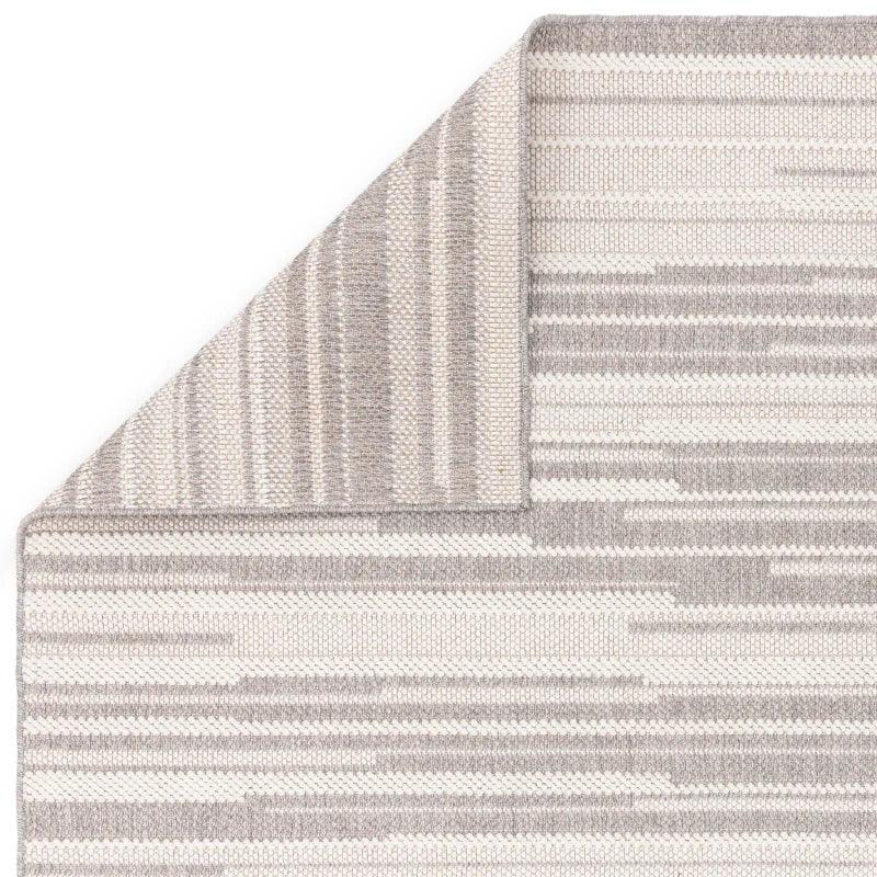 Modern striped area rug in light grey and cream, corner fold shows reversible design