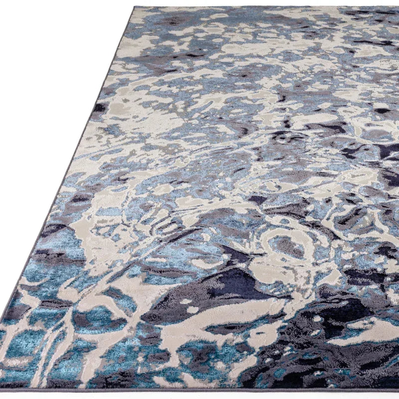 Modern area rug with abstract blue, grey, and cream pattern shown from side angle