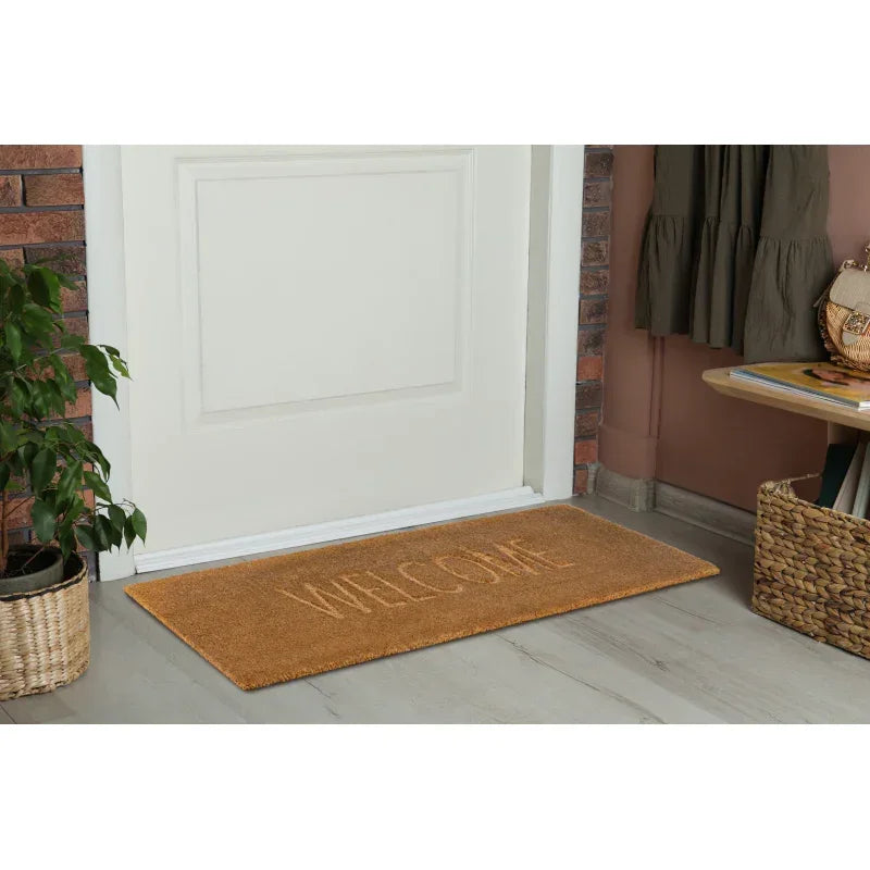 Coir welcome doormat placed at front door entrance on light wood floor