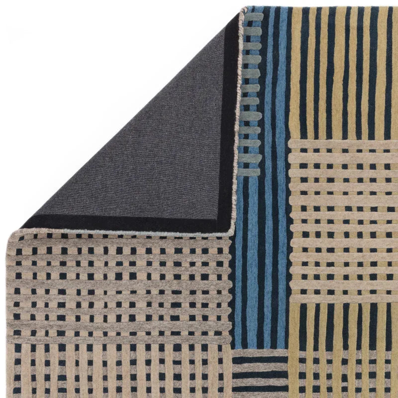 Geometric patterned rug with blue, beige, and green stripes, corner flipped to show backing