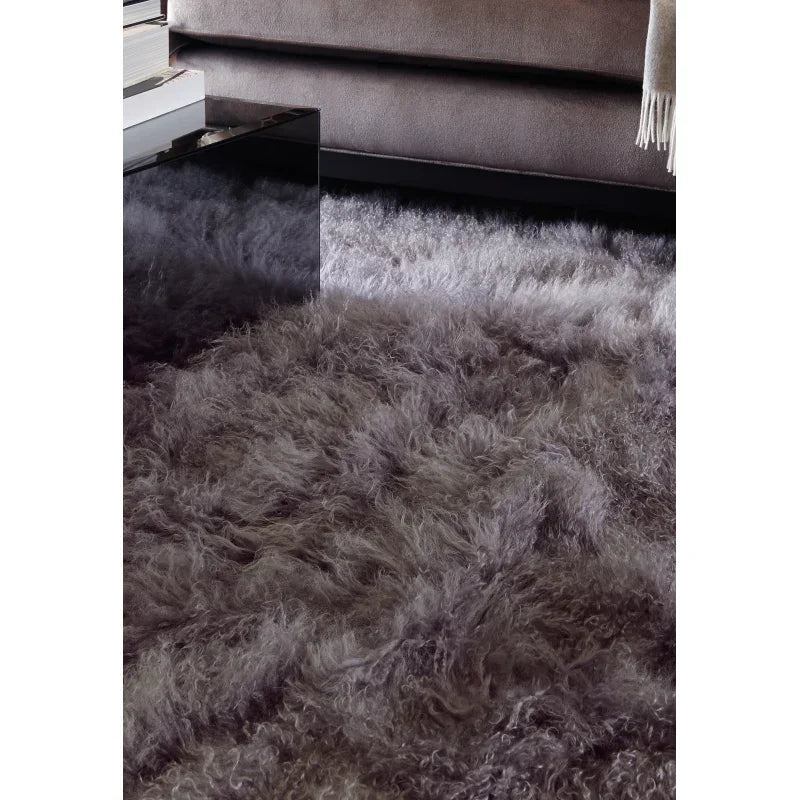 Grey shaggy rug in living room beside velvet sofa and black glass coffee table