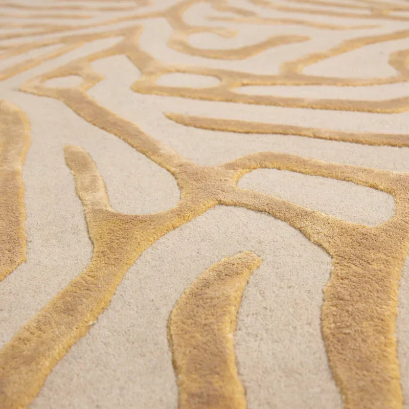 Beige and gold rug with raised abstract pattern, close-up of textured carpet surface