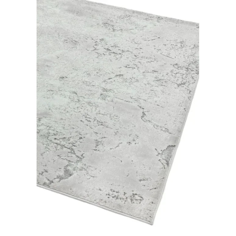 Light grey area rug with subtle marble texture and soft pile, shown from an angled view