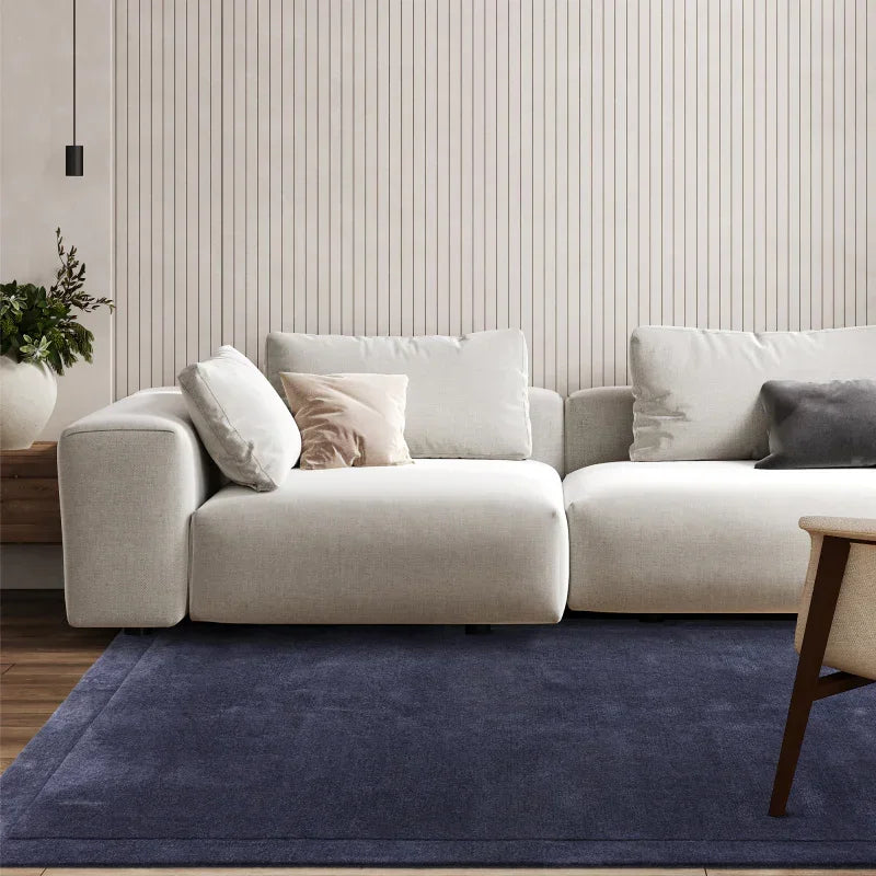 Modern beige fabric sofa with cushions on navy rug in living room